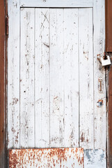 Abandoned house door texture background. Locked wooden entrance with old fashion metal padlock. Blue, white and brown peeled off paint. Security and safety concept. Vertical, close up, copy space