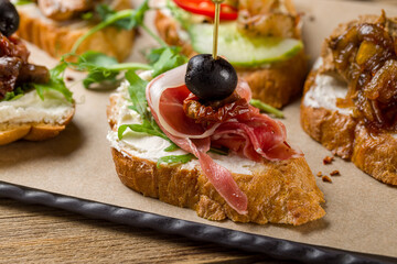 Bruschetta with Parma ham, cheese and olives macro close up