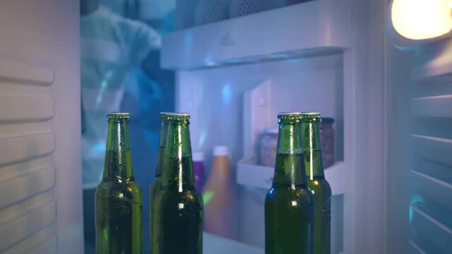 Young African-American ethnicity man taking beer from fridge having party at home. Realtime