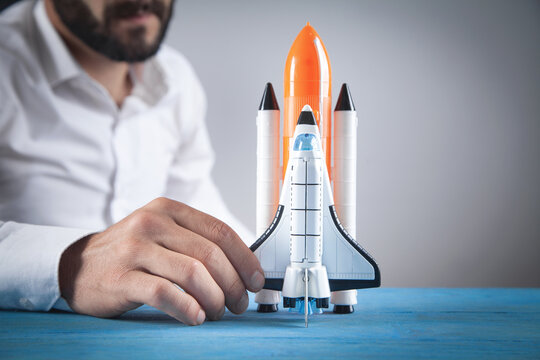 Man holding toy rocket on the desk.