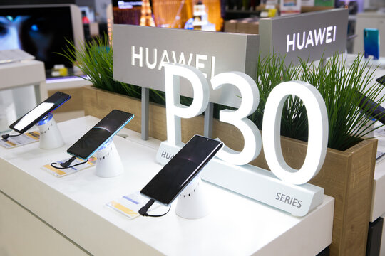 Huawei P30 mobile smartphones on display stand in electronic store. Brand logo sign.