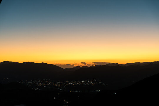 Dramatic image of a Caribbean mountain sunset high in the Dominican Republic with a snall town in the valley with street lights.