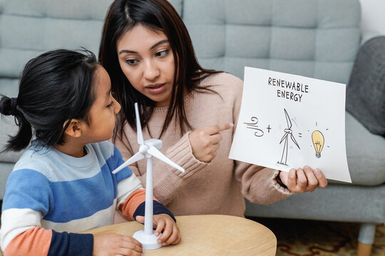 Asian mother working with her child on renewable energy project for school science class at home - Focus on mom right hand