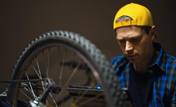 Master with tablet pc examines wheel of the bicycle. Bicycle repair workshop.