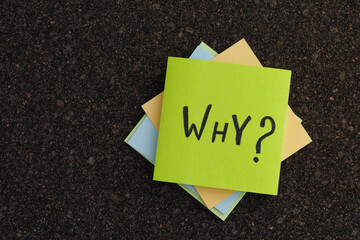 A stack of colorful sticky notes with the Why question on a cork board