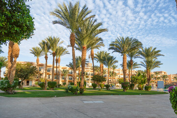 Fototapeta na wymiar Hurghada, Egypt. Egyptian garden with palm trees in hotel .Swimming pool and accommodation at tropical resort. Buildings, swimming pools and a recreation area by the red sea. All iclusive holidays.