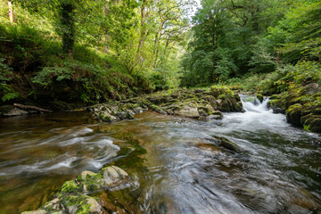 Naklejka na ściany i meble Long exposure of a waterfall on the East Lyn River at Watersmeet in Exmoor National Park