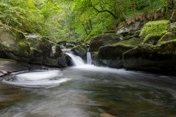 Naklejka na ściany i meble Long exposure of a waterfall on the East Lyn River at Watersmeet in Exmoor National Park