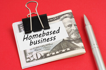 On a red background lies a pen and dollars clamped with a clip with the inscription on paper -...