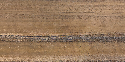 panorama of surface from above of gravel road with car tire tracks