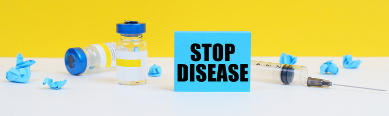 On the table is a syringe, injections and a blue sign with the inscription - STOP DISEASE
