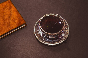 Top view of a cup of coffee and a black leather notebook, isolate on black background