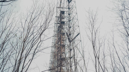 abandoned radio station and trees in chernobyl zone under grey sky.