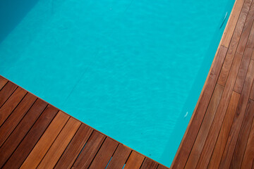 Diagonal lines of wood in detail ipe decking and blue water swimming pool abstract background