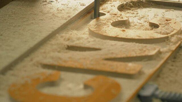 Router cutting machine engraves CNC text on the wood, slow motion shot