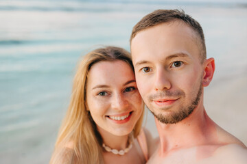 Obraz premium Beautiful couple in love doing self on a tropical beach, enjoy the holidays, sunbathe and have fun.