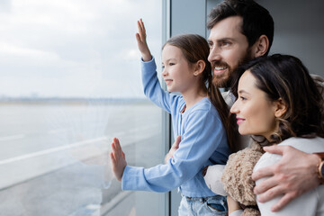 positive family looking at window in airport.