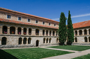Fototapeta premium Corner of the courtyard of the convent of Santo Domingo in Caleruega with two large cypress trees, Burgos, Castilla y León, Spain.