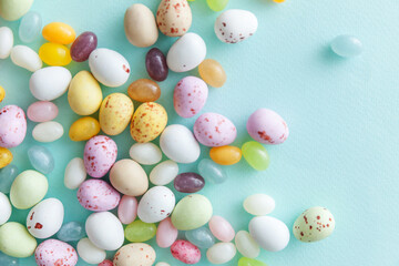 Fototapeta na wymiar Happy Easter concept. Preparation for holiday. Easter candy chocolate eggs and jellybean sweets isolated on trendy pastel blue background. Simple minimalism flat lay top view copy space