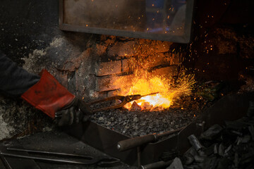 blacksmith warming blank metal on coal fire