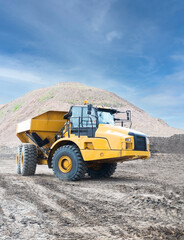 Yellow dump truck on the road construction site against blue sky