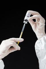 partial view of immunologist in white latex gloves holding syringe and omicron variant vaccine...