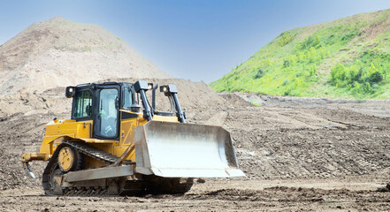 Heavy yellow bulldozer moving soil on the construction site © Aguus
