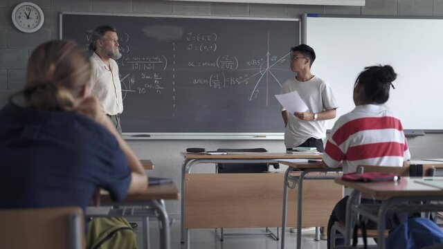 Asian teenager high school student presenting a project or reading a composition to classmates and teacher