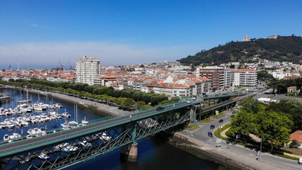 Fototapeta premium Viana do Castelo, Portugal, June 10, 2021: The Gustave Eiffel Bridge over the river Lima in Viana do Castelo. Aerial panoramic cityscape view of Viana and the Marina.