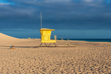 yellow beach hut in the sand at sunset