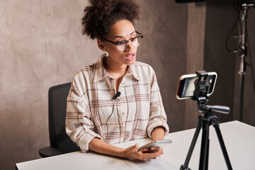 Multiracial woman wearing glasses looking attentively at the camera of her smartphone