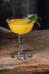 orange juice vodka cocktail with lemon verbena garnish on wood cart