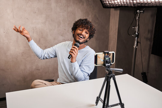 Nice multiracial blogger singing at his studio to microphone