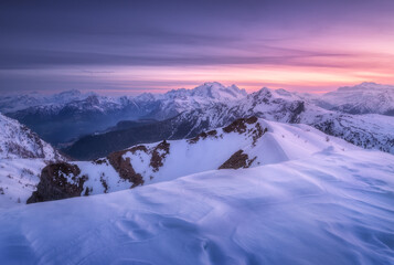 Snow covered mountains and colorful purple sky with clouds at sunset in winter. Beautiful wintry...