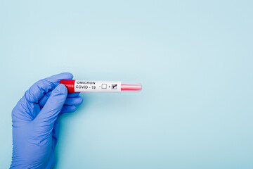 Obraz premium partial view of doctor holding positive covid-19 omicron variant test on blue background.
