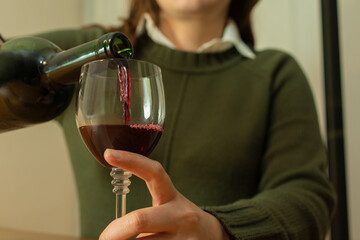 Close-up view of a lonely woman pouring herself a glass of red wine