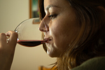 Close-up on a beautiful Hispanic woman drinking red wine from a crystal goblet