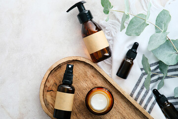 Set of natural organic SPA beauty products on wooden board with eucalyptus leaves. Amber glass cosmetic bottles top view. - obrazy, fototapety, plakaty