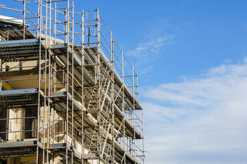 Frame of modern metal scaffolding on a building under construction on a background of blue sky.