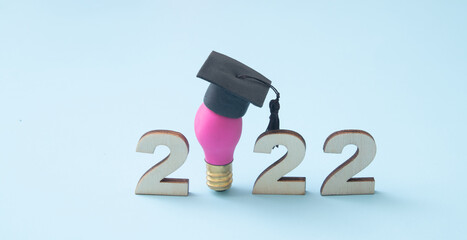 Numbers 2022 with lamp in graduated hat on blue background as symbol idea and creative solutions...