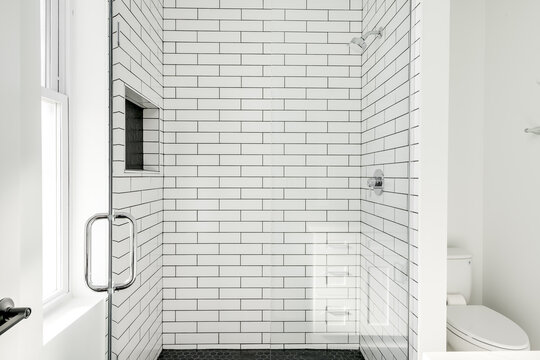 Modern All White Bathroom with White Subway Tile in Shower and Black Hexagon Tile on the Floor