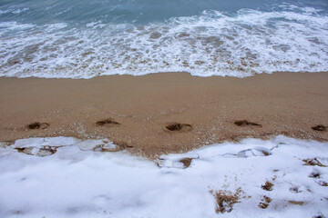 Snow in the beach in Barceloneta, Barcelona
snow in the sand on the beach with footprints on the sand
Snow, sand and sea