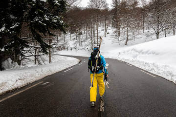 Young caucasian skier going uphill on a snowy road on the Pyrenees.
