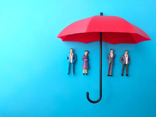 Miniature people cover by red umbrella on a blue background. Human or employee protection,insurance...