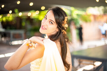 Young woman dressed in a yellow party dress smiling at camera. Wedding guest.