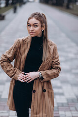 Young beautiful girl in a beige jacket posing on the streets of the city. clothing