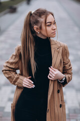 Young beautiful girl in a beige jacket posing on the streets of the city. clothing