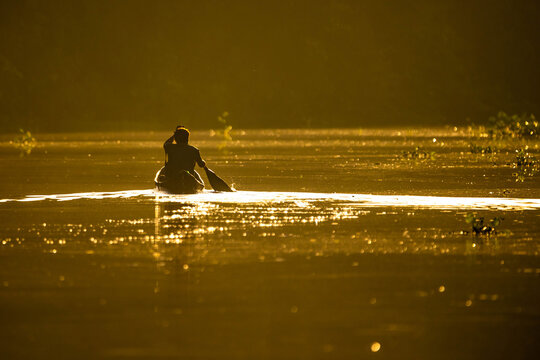 Scenic view of fisherman in canoe at sunrise on the river