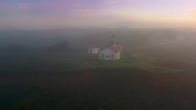 Coastal lighthouse. Point Cabrillo Light station coastal lighthouse at west coast of Unites States of America. Light comes from glass lantern lens illuminating thick morning fog above ocean at sunrise