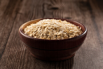 Oat flakes in wooden bowl.